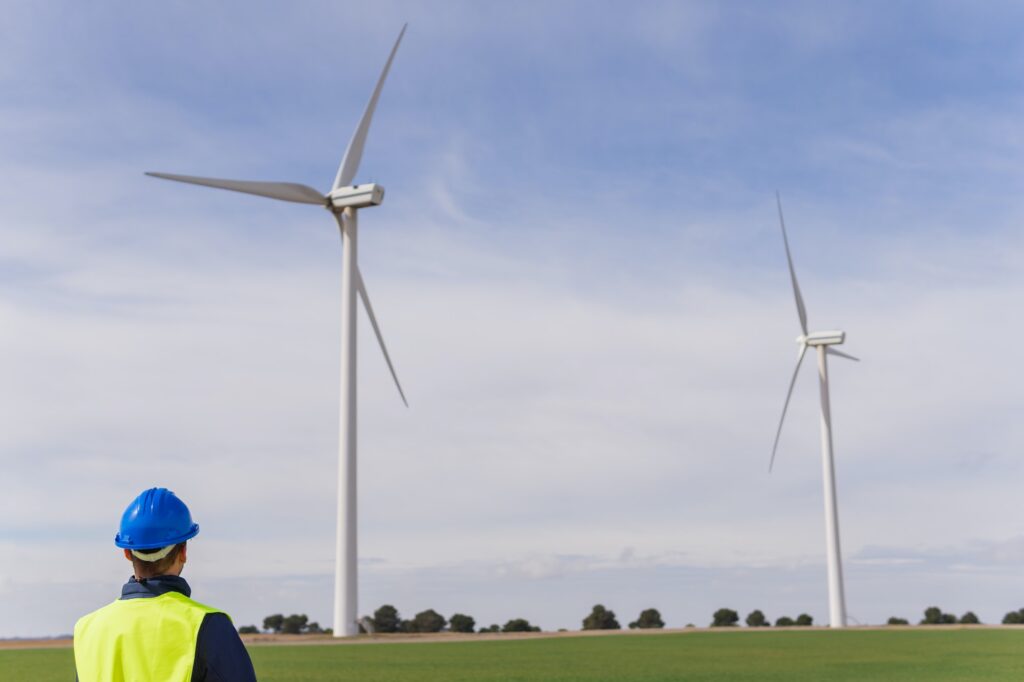 Unrecognizable person looking at electrical generators in a wind farm